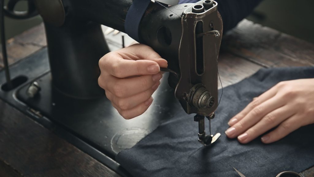 experienced tailor stitching on a piece of cloth